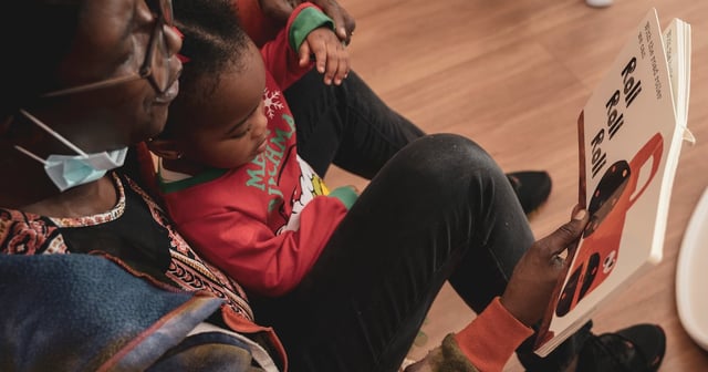 A teacher reads a book to a young student.
