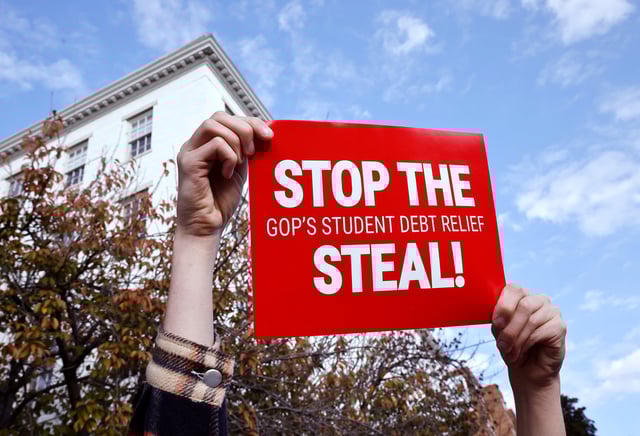 A person holds a sign reading "STOP THE GOP STUDENT DEBT RELIEF STEAL"