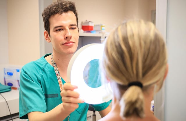 Un residente en Dermatología en la Fe analiza la piel de una paciente.
