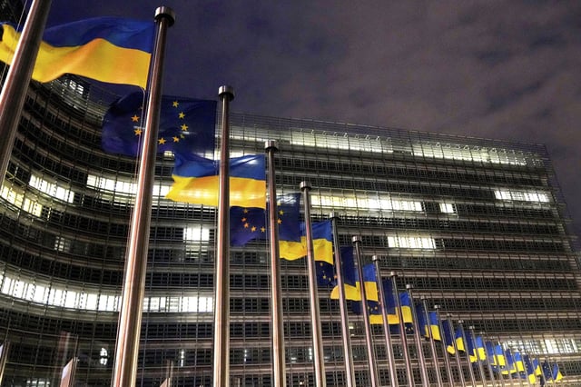 The European Union and Ukrainian flags flap in the wind to mark the third anniversary of Russia's full-scale invasion of Ukraine outside EU headquarters in Brussels, Monday, Feb. 24, 2025. (AP Photo/Virginia Mayo)