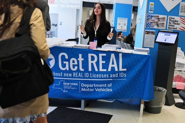 An employee checks people in behind a banner for REAL ID at the New York State DMV on April 28, 2025 in New York City. (Photo by Michael M. Santiago/Getty Images)