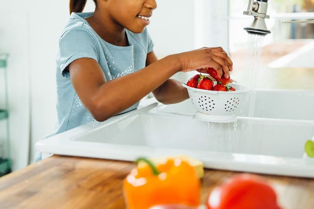 Black girl washing strawberries in kitchen