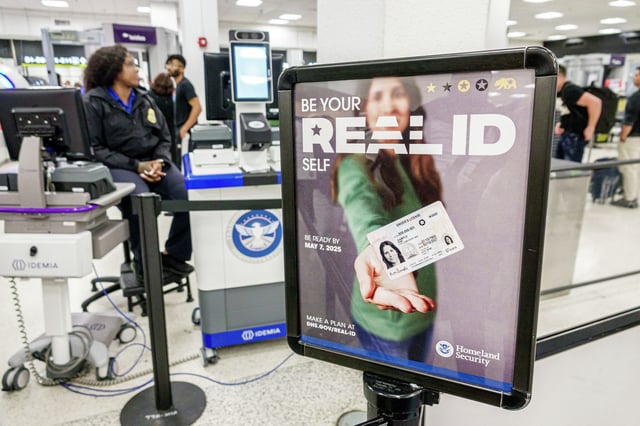 A Homeland Security poster at Miami International Airport reminds travelers they will need a Real ID to fly after May 7, 2025. 