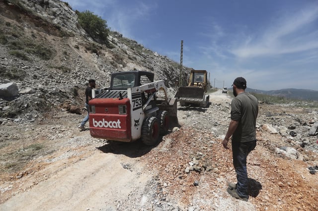 Workers close a crater following Israeli airstrikes that targeted hilltops near Nabatieh town, south Lebanon, Thursday, May 8, 2025. (AP Photo/Mohammed Zaatari)