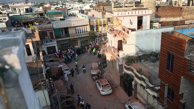 People gather near houses and vehicles damaged due to an attack from Pakistan, in Jammu, on Saturday, May 10, 2025.