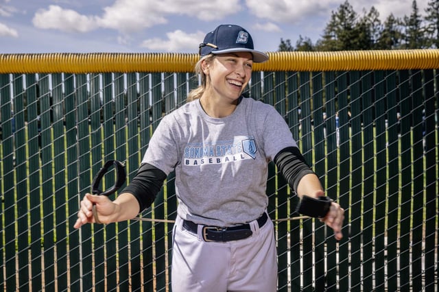 Marika Lyszczyk, a sophomore pitcher on the Sonoma State baseball team, stretches during practice in Rohnert Park in 2023. She is the first female baseball player at the school and California Collegiate Athletic Association.  A court has ruled that Sonoma State can proceed with eliminating its Division II athletics program, as well as six academic departments. 