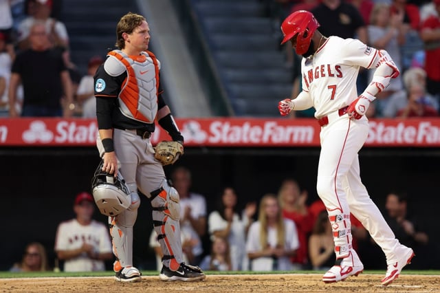 Angels’ Jo Adell (7) reaches home plate after hitting a home run as Baltimore Orioles catcher Adley Rutschman, left, looks on during the fourth inning of a baseball game in Anaheim, Calif., Saturday, May 10, 2025. (AP Photo/Jessie Alcheh)