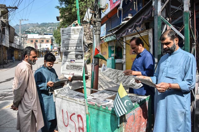 Vecinos de Muzaffarabad, la capital de la región de Cachemira administrada por Pakistán, leen los diarios tras la declaración de alto el fuego.
