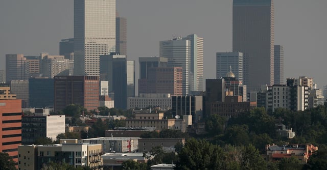 A smoky haze envelopes the skyscrapers and Rocky Mountains that usually can be seen as a backdrop to the city from a high-rise building Monday, Aug. 20, 2018, in Denver. Smoke from the countless wildfires burning in western Canada as well as the American West has forced the issuance of air quality alerts across the region. (AP Photo/David Zalubowski)