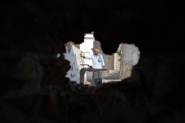 A villager shows the wall of his house riddled with shrapnels from Pakistani artillery shelling at RS Pura, along the International Border, India, Monday, May 12, 2025. (AP Photo/Channi Anand)