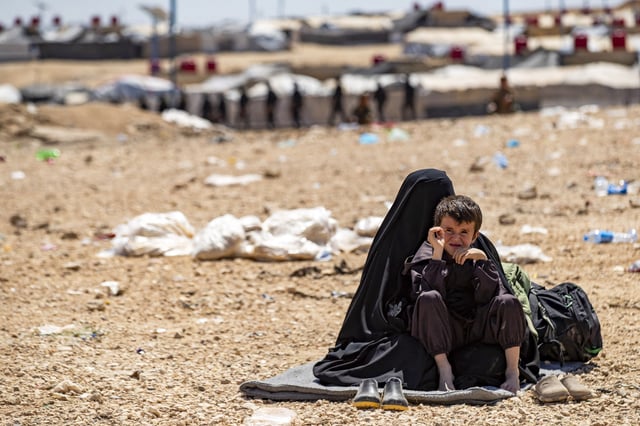 A woman and child sit at the Kurdish-run al-Hol camp, which holds relatives of suspected Islamic State (IS) group fighters in the northeastern Hasakeh governorate, on April 18, 2025, as the Syrian Democratic Forces mount a security campaign against IS &#34;sleeper cells&#34; in the camp.