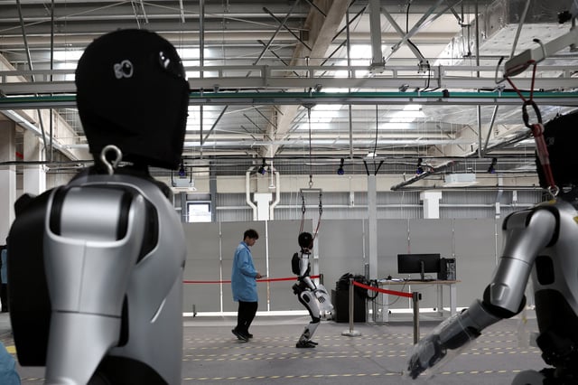 A humanoid robot walks as employees conduct tests on the robots, on the production line at the AgiBot factory in Shanghai, China March 20, 2025. REUTERS/Florence Lo