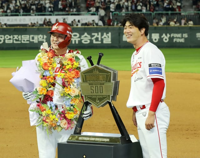 Choi Jeong of the SSG Landers (L) stands next to a plaque commemorating his 500th career home run in the Korea Baseball Organization during a regular-season game against the NC Dinos at Incheon SSG Landers Field in Incheon, just west of Seoul, on May 13, 2025, in this photo provided by the Landers. (PHOTO NOT FOR SALE) (Yonhap)