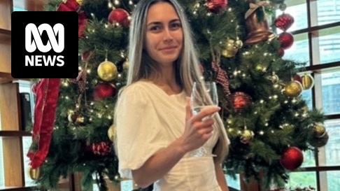 a woman standing in front of a christmas tree in a white dress