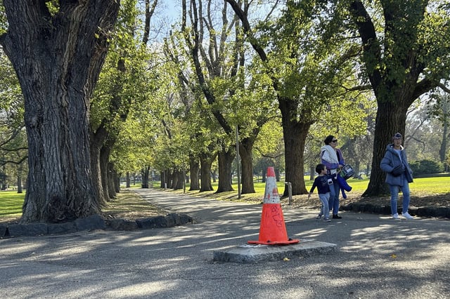 People walk near a traffic cone where a monument of British explorer Capt. James Cook once stood before it was removed following continued vandalism at a park Melbourne, Australia, Wednesday, May 14, 2025. (AP Photo/Rod McGuirk)
