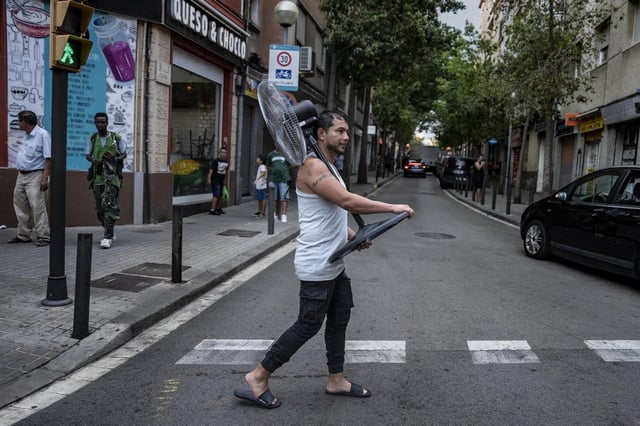 Un hombre carga con un ventilador por la calle en plena ola de calor en el barrio de La Florida, en L'Hospitalet.