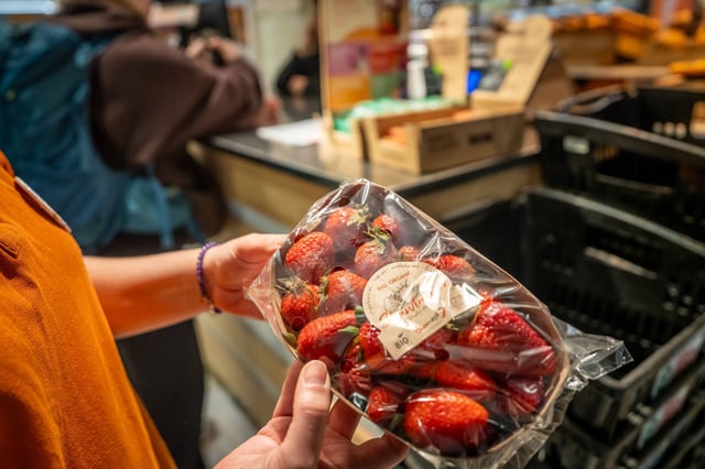 Una mujer observa una bandeja de fresas a punto de caducar en una tienda de Barcelona.