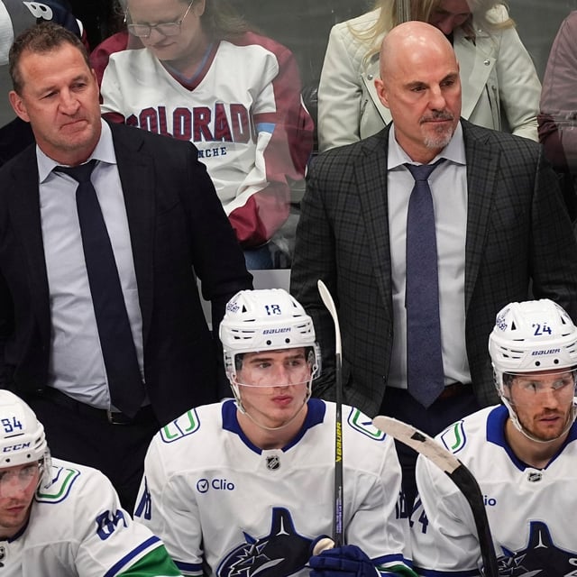 Vancouver Canucks assistant coach Adam Foote, back left, and head coach Rick Tocchet look on from the team box in the third period of an NHL hockey game against the Colorado Avalanche Thursday, April 10, 2025, in Denver. (AP Photo/David Zalubowski)