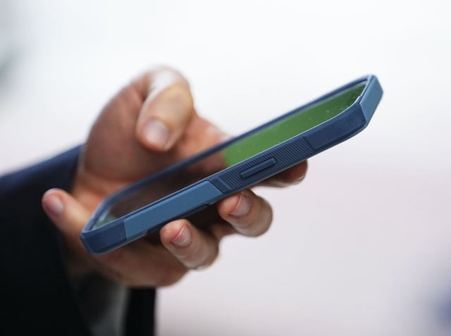 Canada's Big Three telecommunications carriers say they are taking in less revenue from roaming so far this year as fewer Canadians travel to the U.S. amid the ongoing trade war. A person uses a cell phone in Ottawa, Monday, July 18, 2022. 