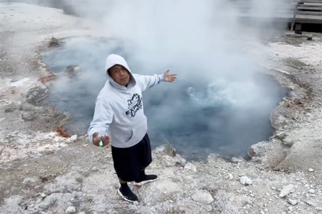 In a screenshot from his May 4 YouTube video, musician Doeboi909 stands away from the boardwalk and near a hot spring in Yellowstone National Park. 