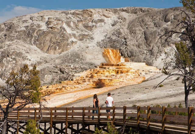 Visitors walk on the designated boardwalk as they pass by Palette Hot Spring at Mammoth Hot Springs inside Yellowstone National Park.