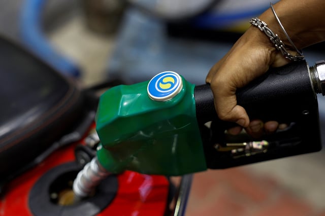 A worker holds a nozzle to pump fuel into a two-wheeler vehicle at a Bharat Petroleum oil and fuel station in Kolkata, India, August 7, 2024. REUTERS/Sahiba Chawdhary/File Photo