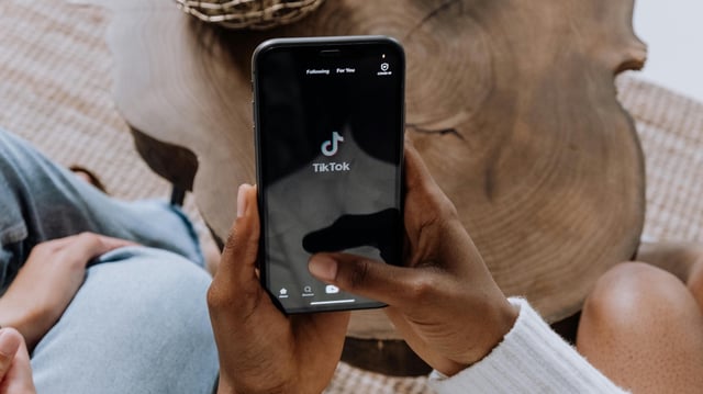 Frau hält ein Smartphone mit TikTok-App in der Hand