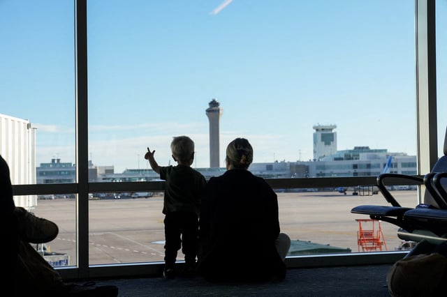 The air traffic control tower is seen from the gate as a woman and a child look out at the Denver International Airport terminal, in Denver, Colorado, U.S., May 15, 2025.  REUTERS/Megan Varner