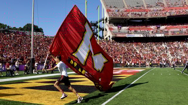Towson at University of Maryland football. A runner carries a Maryland flag on the field during a break in the game&#39;s first quarter. Sept. 2, 2023