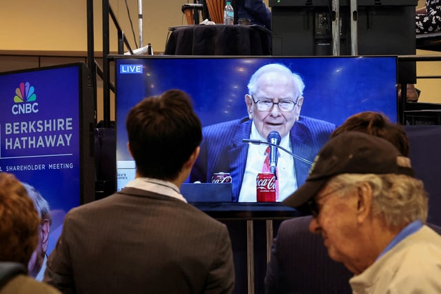People watch as Berkshire Hathaway chairman Warren Buffett is seen on a screen speaking at the Berkshire Hathaway Inc annual shareholders' meeting, in Omaha, Nebraska, U.S., May 3, 2025.  REUTERS/Brendan McDermid/File Photo