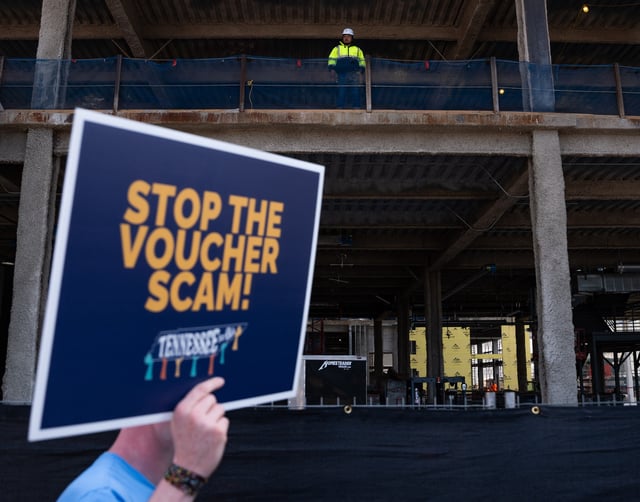 A construction worker looks on as educators and various organizations from across the state of Tennessee march to the Amazon headquarters in downtown Nashville in protest of Governor Bill Lee&#39;s school voucher program on March 12, 2024, in Nashville, Tennessee.
