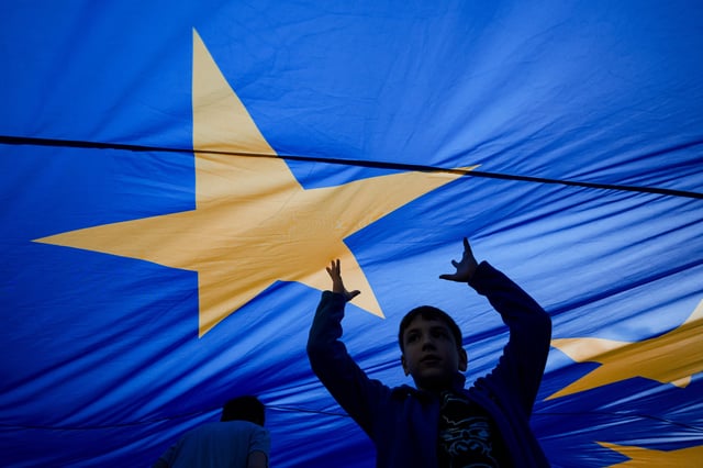 FILE - Children play under an European Union flag during an electoral rally of presidential candidate Nicusor Dan, a week ahead of the second round of the country's presidential election redo in Bucharest, Romania, Sunday, May 11, 2025. (AP Photo/Andreea Alexandru, File)