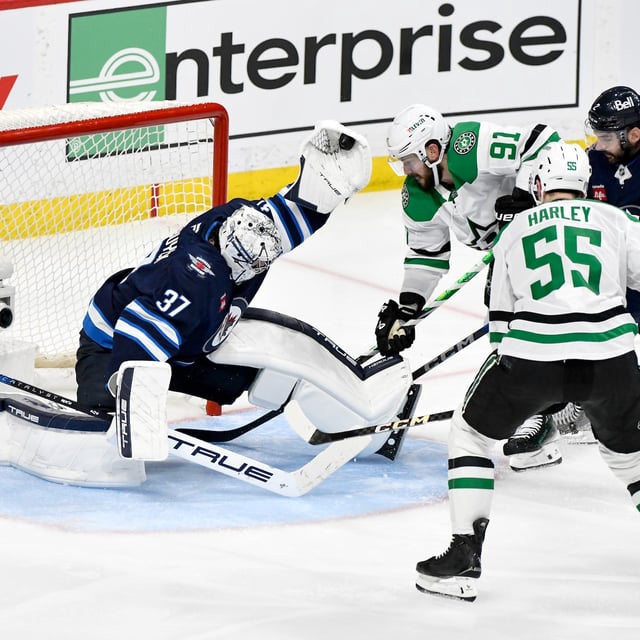 Winnipeg Jets goaltender Connor Hellebuyck (37) makes a save on a Dallas Stars shot as Tyler Seguin (91) and Thomas Harley (55) look for the rebound during second period NHL playoff hockey action in Winnipeg, Thursday, May 15, 2025. THE CANADIAN PRESS/Fred Greenslade