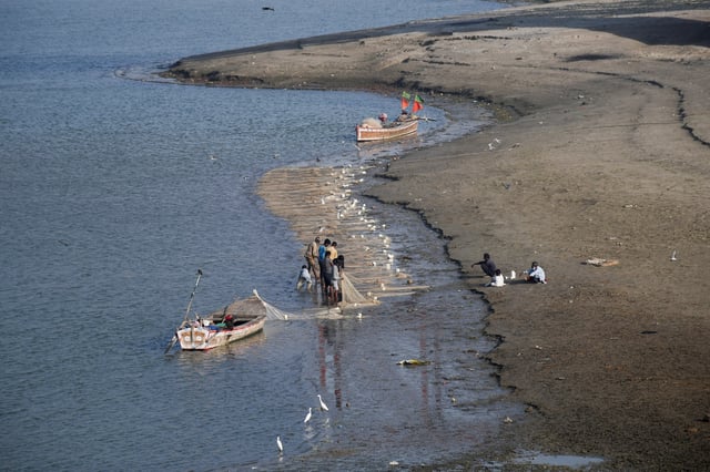 Fishermen clear a fishing net in the water on the partially dried up riverbed of the Indus River in Hyderabad, Pakistan April 25, 2025. REUTERS/Yasir Rajput/File Photo