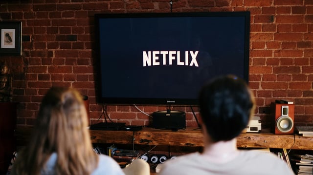 Mann und Frau sitzen vor einem TV und gucken Netflix