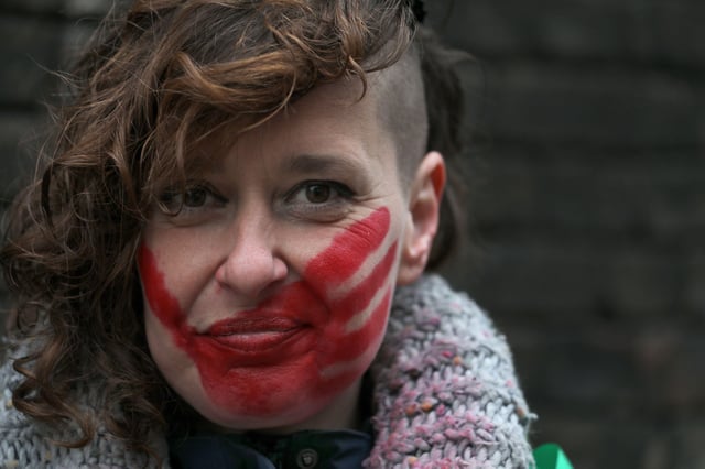 A protester displays a large red handprint across her face during the Women in Cambridge march highlighting the fact that violence against women and girls has increased since 2018. Photo: ZUMA Press, Inc. / Alamy