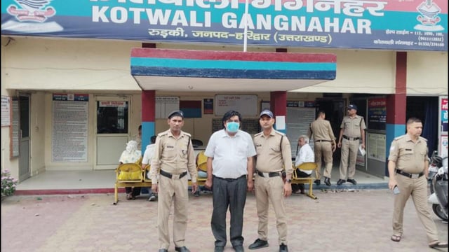 The accused (centre) in police custody. (Sourced photo)