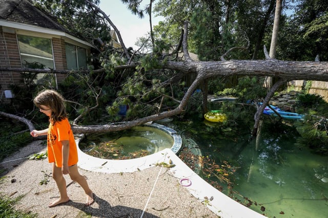 Bailey Hatfield walks past a toppled tree in the backyard of her home on June 22, 2023, in Spring after an overnight storm blew through the area, knocking out power and downing trees.