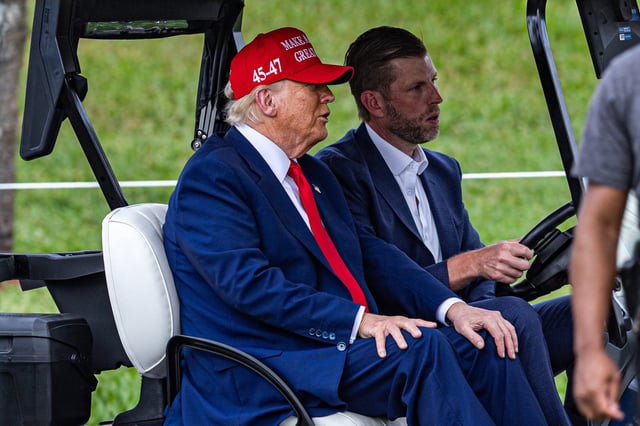 President Donald Trump rides in a golf cart with his son Eric Trump, who is an executive vice president of the Trump Organization.