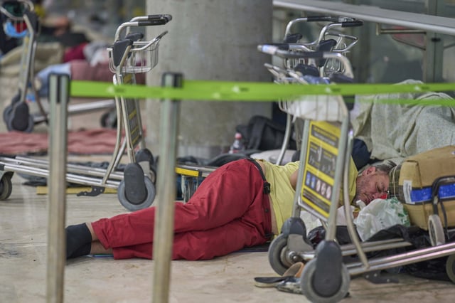 A person sleeps on the floor of Terminal 4 at Adolfo Suarez-Madrid Barajas Airport in Madrid, Spain, Thursday, May 15, 2025. (AP Photo/Manu Fernandez)