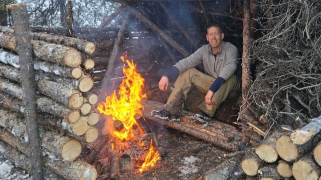 Outdoor Boys Luke Nichols in front of a fire