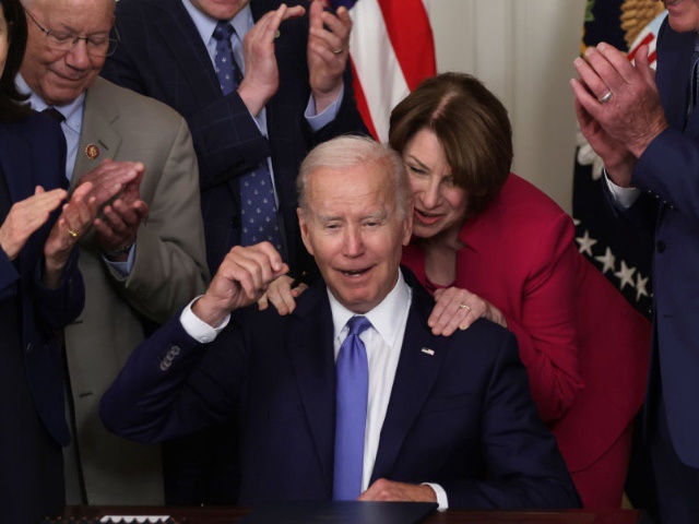 WASHINGTON, DC - JUNE 16: U.S. Sen. Amy Klobuchar (D-MN) gives President Joe Biden a hug after she was handed his signing pen as Sen. Maria Cantwell (D-WA) (L), Rep. Pete DeFazio (D-OR) (2nd L), Rep. John Garamendi (D-CA) (R) look on during a bill signing event at the State Dining Room of the White House June 16, 2022 in Washington, DC. President Biden signed the Ocean Shipping Reform Act of 2022 into law.