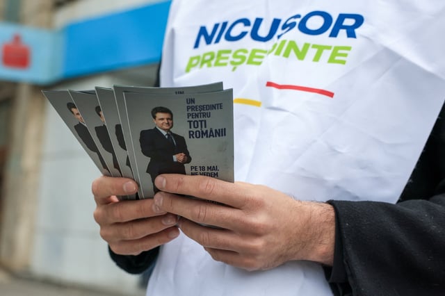 Un militant tient des tracts présentant le candidat présidentiel et maire de Bucarest, Nicusor Dan, à Bucarest, Roumanie, le 16 mai 2025.