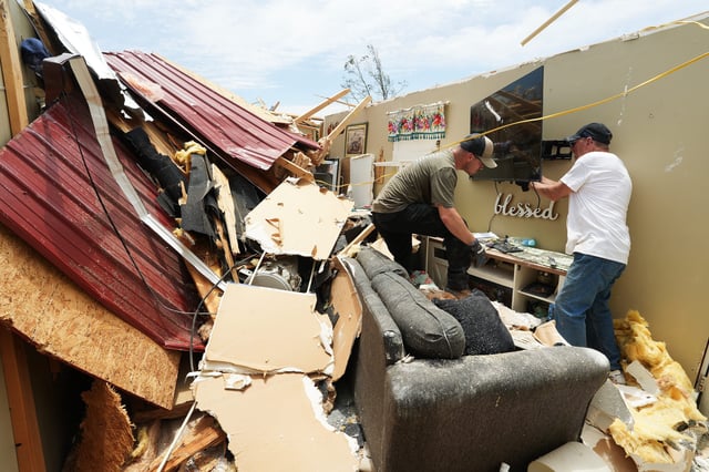 Clayton Frusco, left, helps homeowner Charles Simpson remove a new televison from his property after a tornado tore through the Sublimity neighborhood along Miller Lane in London, Ky. on May 18, 2025.