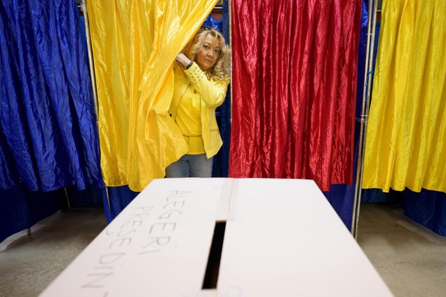 Une femme sort d’une cabine de vote aux couleurs du drapeau roumain lors du second tour de l’élection présidentielle à Bucarest, en Roumanie, dimanche 18 mai 2025.