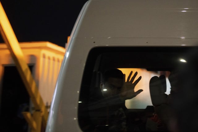 Migrants who were deported from the U.S. to Mexico wave as they are transported to a shelter, as they cross El Chaparral pedestrian border bridge in Tijuana, Mexico, late Tuesday, Jan. 21, 2025.