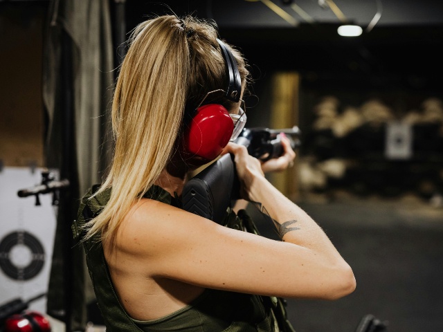 woman in tank top holding black rifle