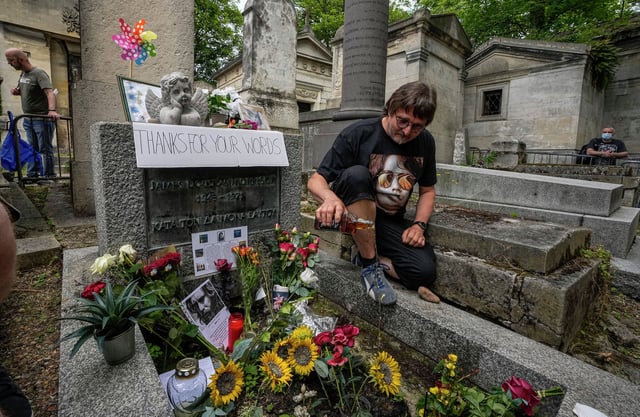 Torsten Marquardt of Germany pours some whiskey on the tomb of rock singer Jim Morrison at the Pere-Lachaise cemetery in Paris in 2021. Fans across Europe gathered at the grave of rock legend Jim Morrison to mark the 50th anniversary of his death.