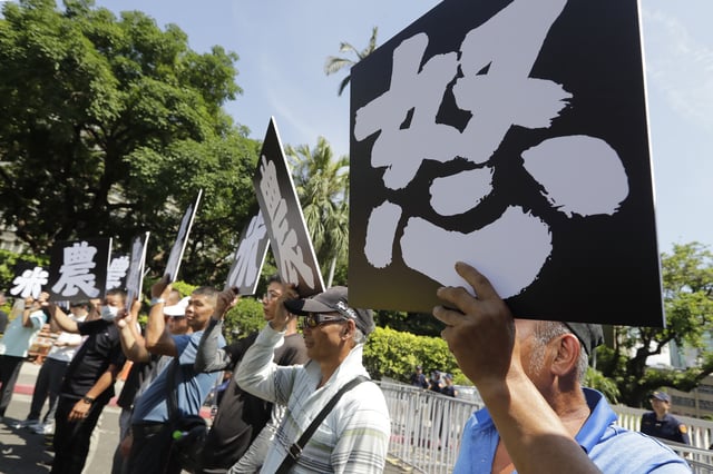 Taiwanese farmers hold slogans reading ''Rice Farmers Angry'' to protest against the government's plan to reduce the import tariffs on American agricultural products to zero in Taipei, Taiwan, Friday, May 16, 2025. (AP Photo/Chiang Ying-ying)