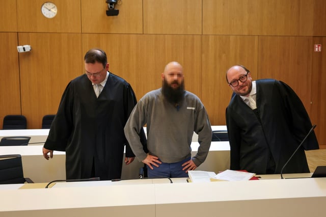 Defendant Dieter S, stands between his lawyers Stephan Schultheis (L) and Michael Loewe (R) as he arrives to his trial for spying for Moscow and readying attacks on critical military infrastructure and industry in a court in Munich, southern Germany, on May 20, 2025. Three German-Russian dual nationals will go on trial in Munich on May 20, accused of spying for Moscow and readying attacks on critical military infrastructure and industry. The main suspect, named only as Dieter S, is said to have been at the centre of a plot to undermine Germany's support for Ukraine through acts of sabotage aimed at targets including US military bases.